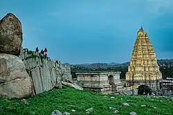 Panoramic high-angle view of the Virupaksha Temple complex and the surrounding boulder-strewn landscape of Hampi, seen from a nearby hilltop.