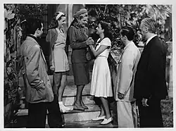 Black and white photograph on Ridax glossy photographic paper with a white border. Scene from the film La Gata (1947), with six actors standing on the exterior steps of a house. From left to right: Horacio Priani, Nélida Bilbao, Zully Moreno, Sabina Olmos, Enrique Álvarez Diosdado, and Adolfo Linvel.
