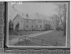 A black and white photograph of a two-story manor house, viewed from the front.