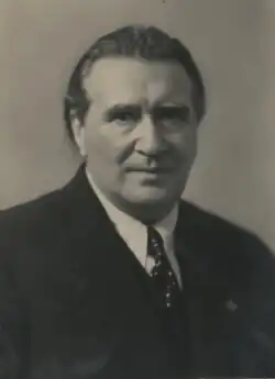A black and white photograph of a man in half-bust lenght