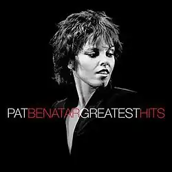 black and white half-length photo of Pat Benatar in black top looking to side over black background