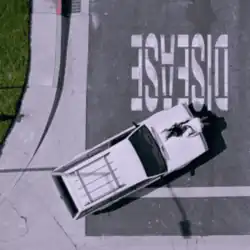 A white car parked beneath upside down text reading "Disease". A woman with black hair is lying across the hood of the car.