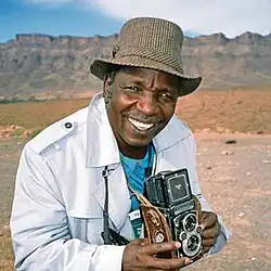 The image features Malick Sidibé, a celebrated Malian photographer