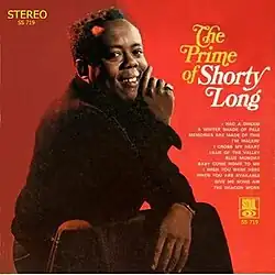 Long seated and looking toward the camera, smiling
