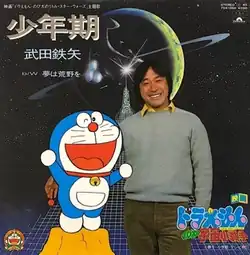 Tetsuya Takeda holding Doraemon on the album. It has "映画「ドラえもん のび太のリトル・スター・ウォーズ」主題歌 少年期 武田鉄矢 b/w 夢は荒野を" at upper left, "STEREO 45, 7DX 1360 ¥700, Polydor" at upper right, and "ドラえもん のび太の宇宙小戦争" at lower right