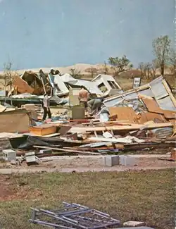 A home that was destroyed by the tornado, with multiple people looking at the damage