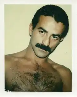 Shirtless man with curly hair and a thick mustache