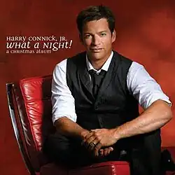 Connick sitting on a red chair and looking towards a camera